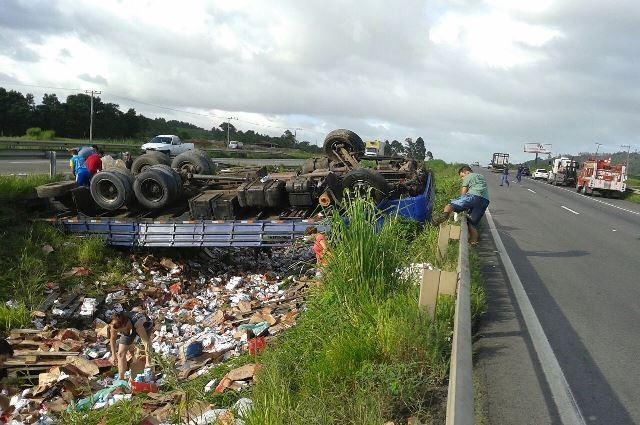 Caminhão capota e carga de leite é saqueada